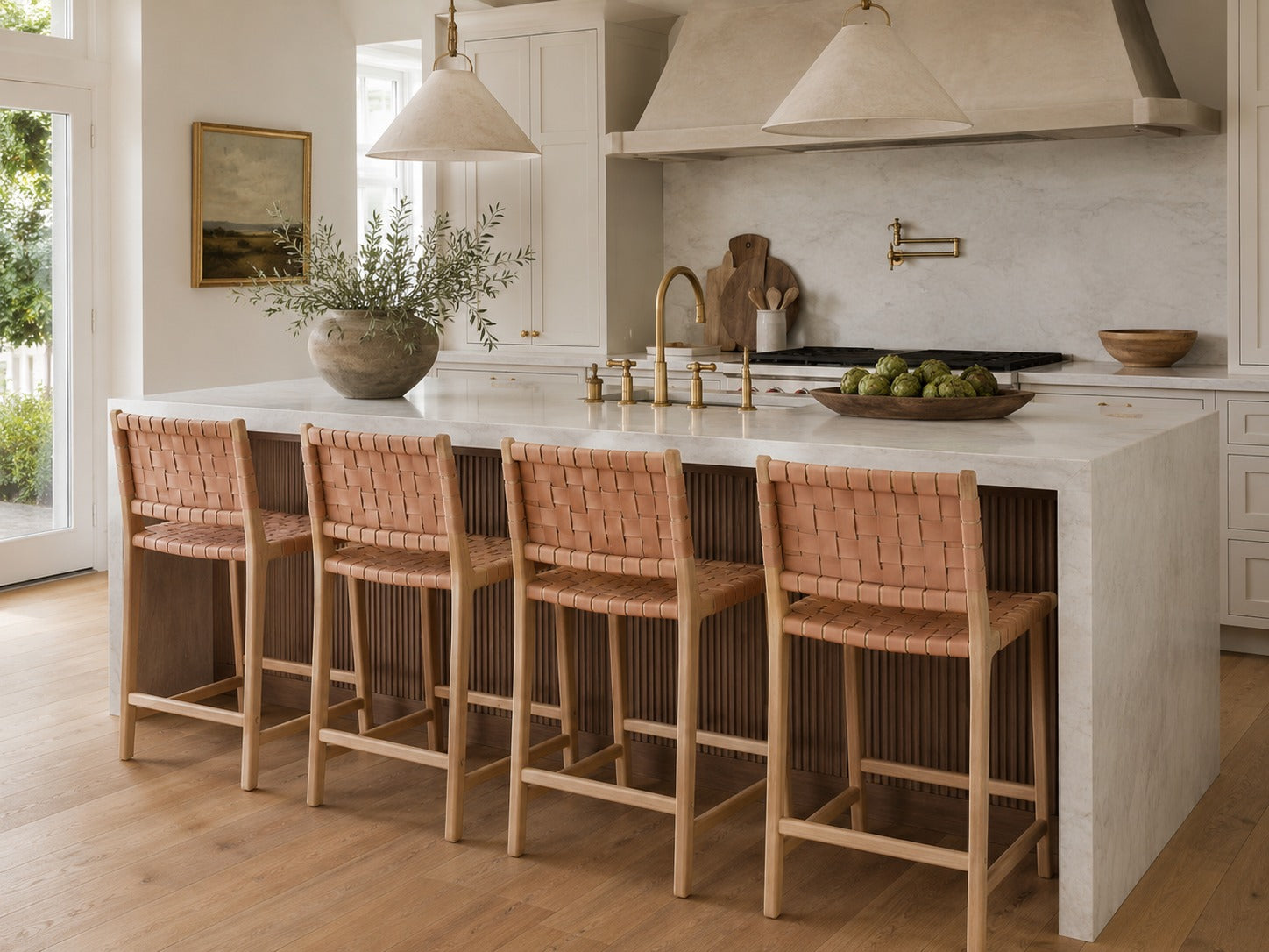 Modern kitchen with a white island and woven bar stools.