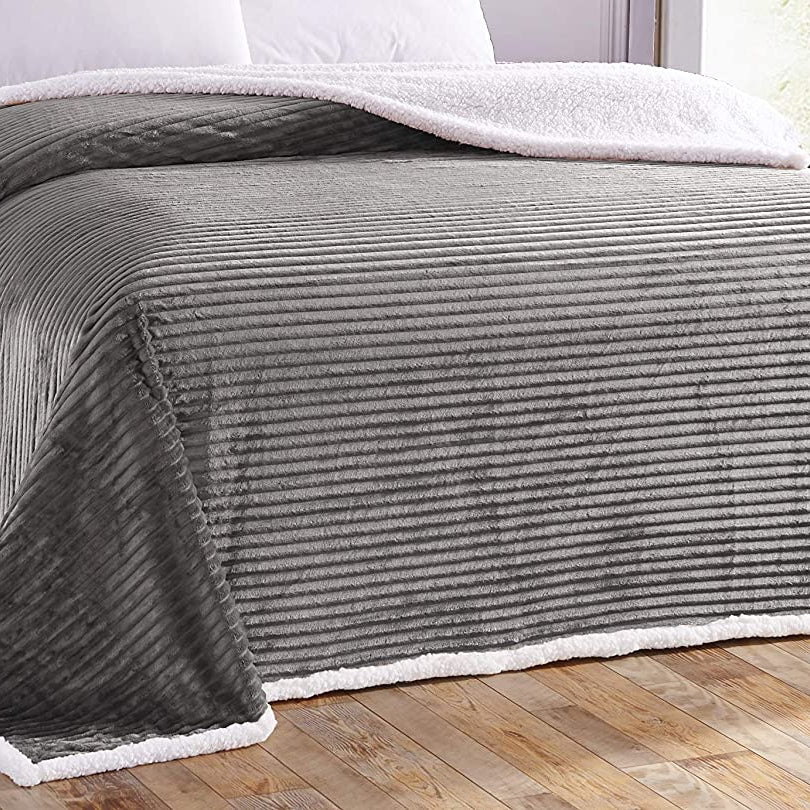 Gray striped blanket draped over a bed in a bedroom setting