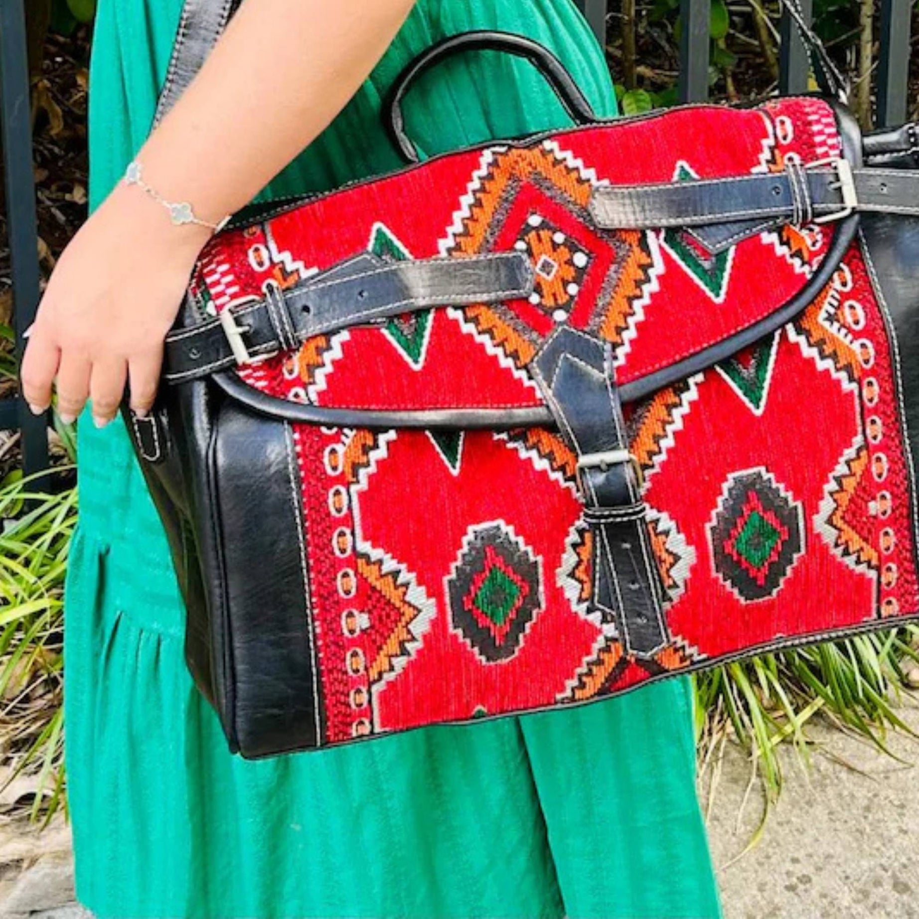 Person holding a red patterned handbag with black accents