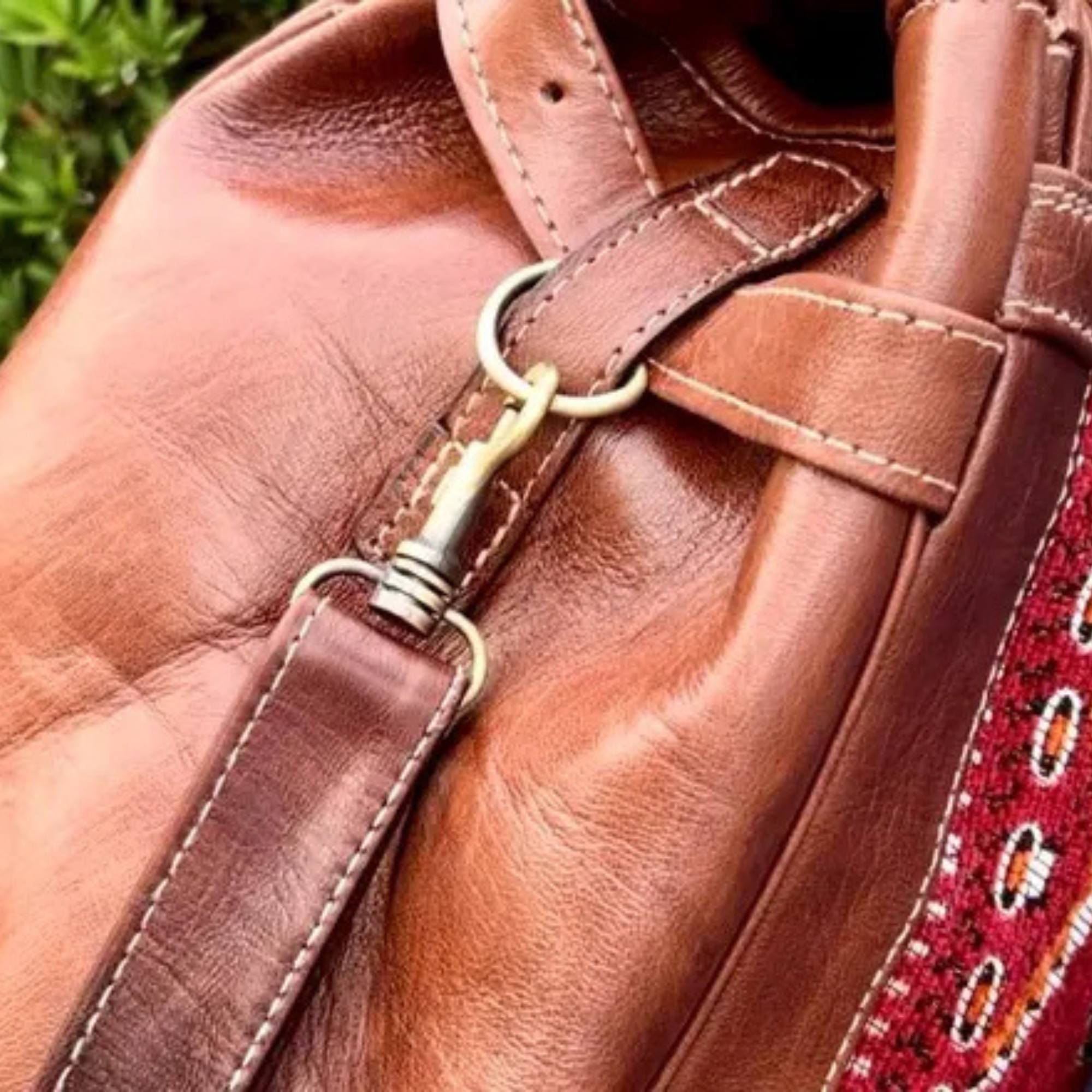Close-up of a brown leather bag with a strap and decorative element.