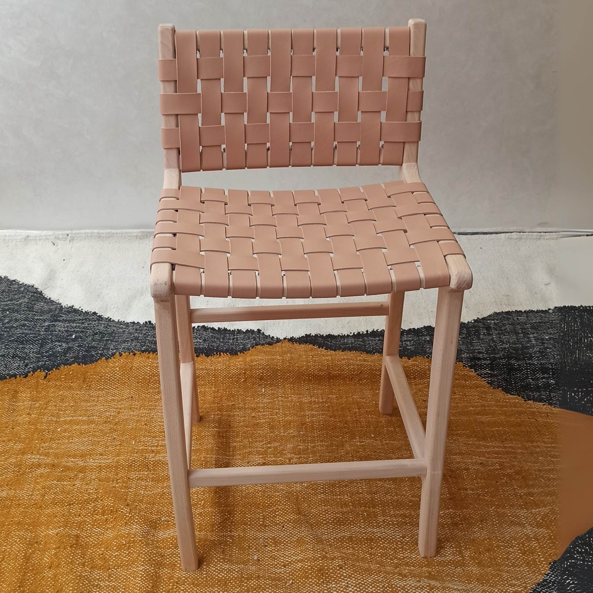 Pink woven chair on a textured surface with a neutral background