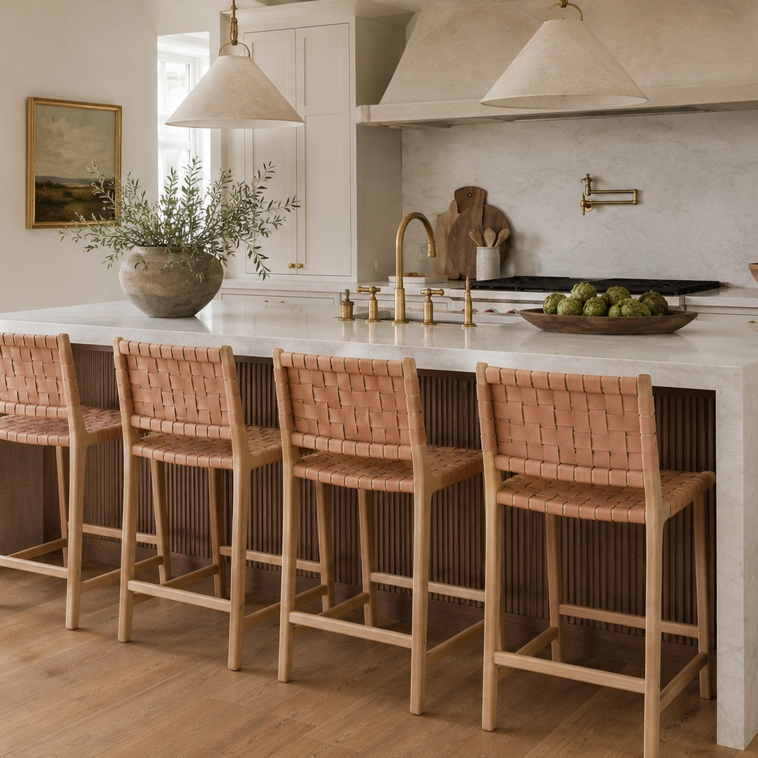 Modern kitchen with a white island and woven bar stools.