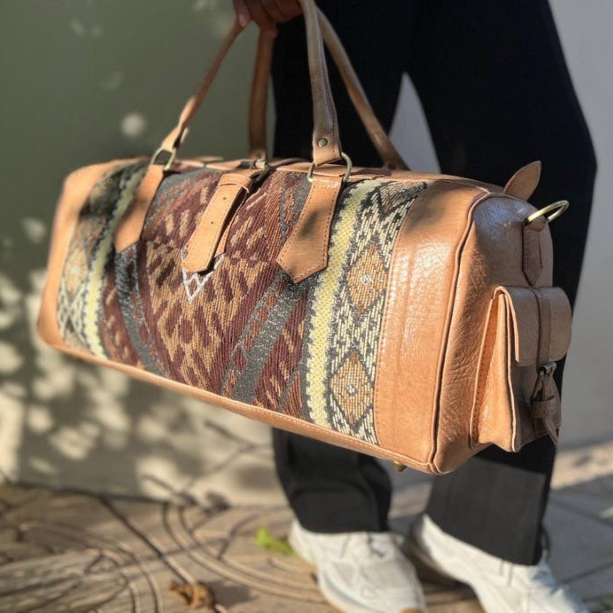 Person holding a patterned duffel bag with a neutral background