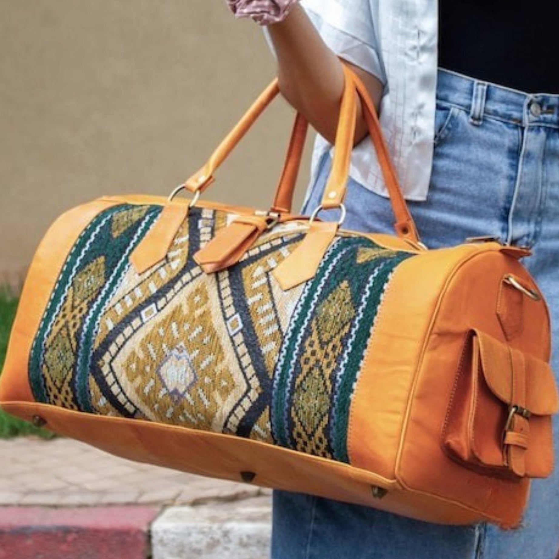 Person holding a patterned duffel bag with orange accents