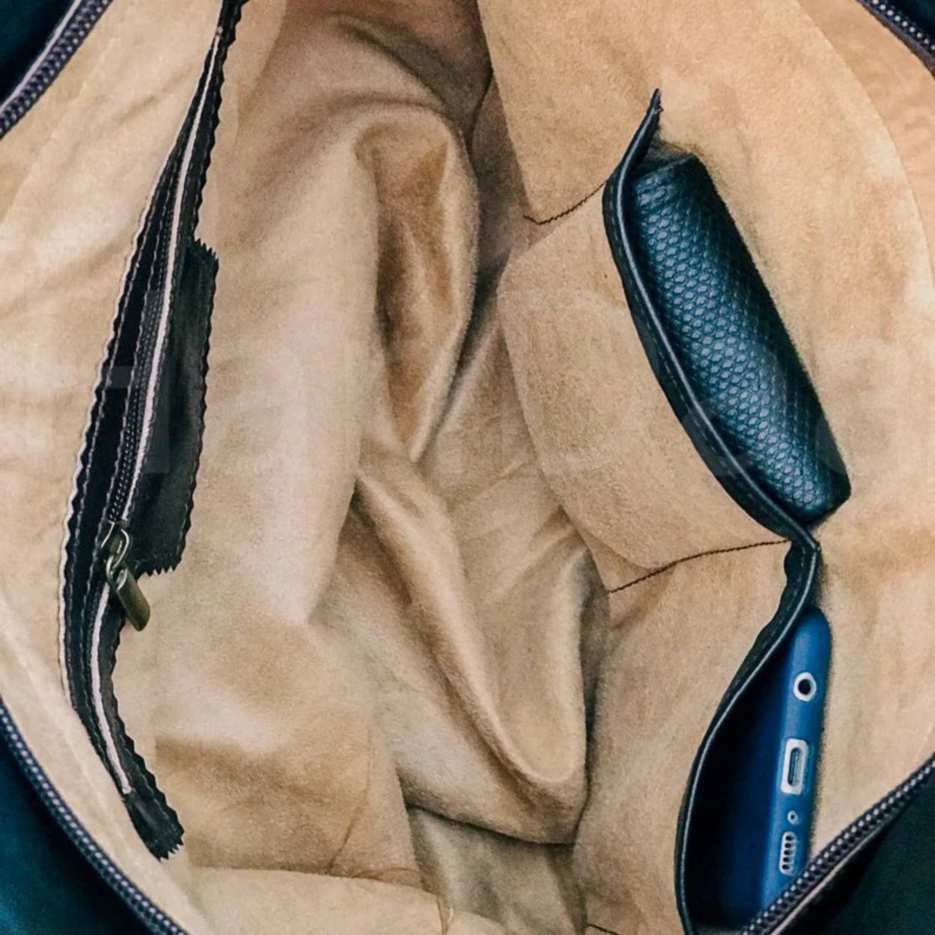 Close-up of a blue electronic device with black textured grip on a beige textured surface