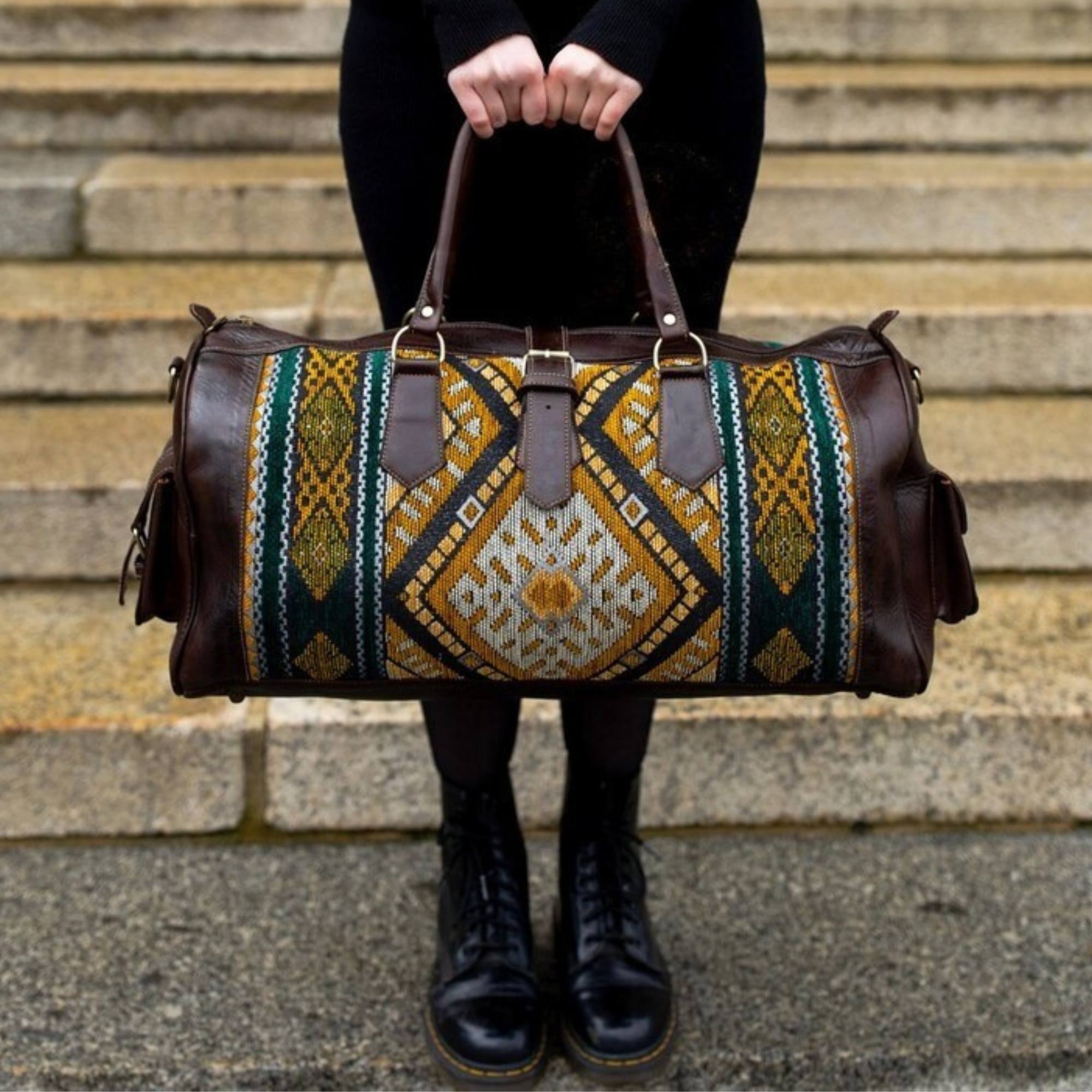 Person holding a patterned duffel bag on stone steps