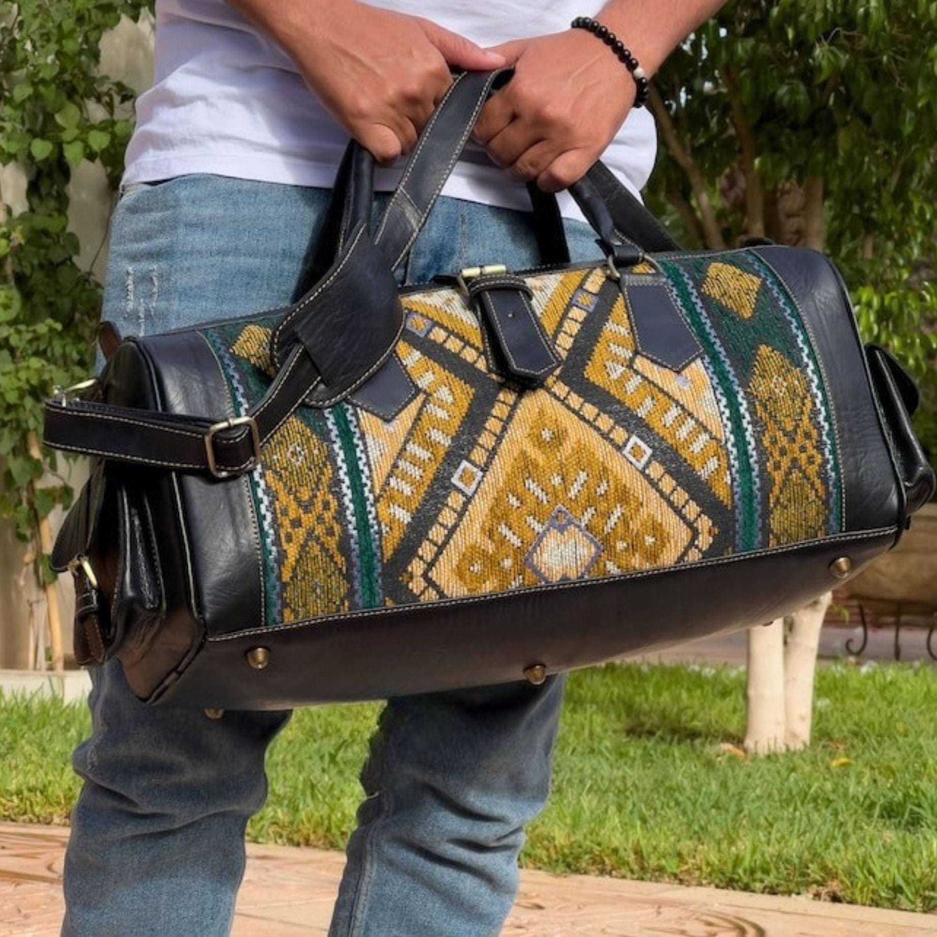 Person holding a patterned duffel bag outdoors